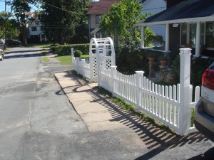Vinyl picket fence with new england post caps and palace solar cap on the corner posts and grand arbor over opening